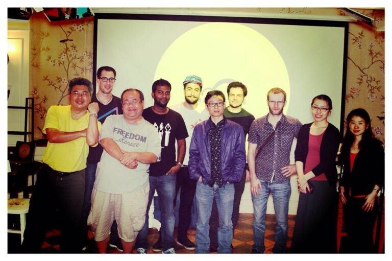 A group of designers posing in front of a presentation screen