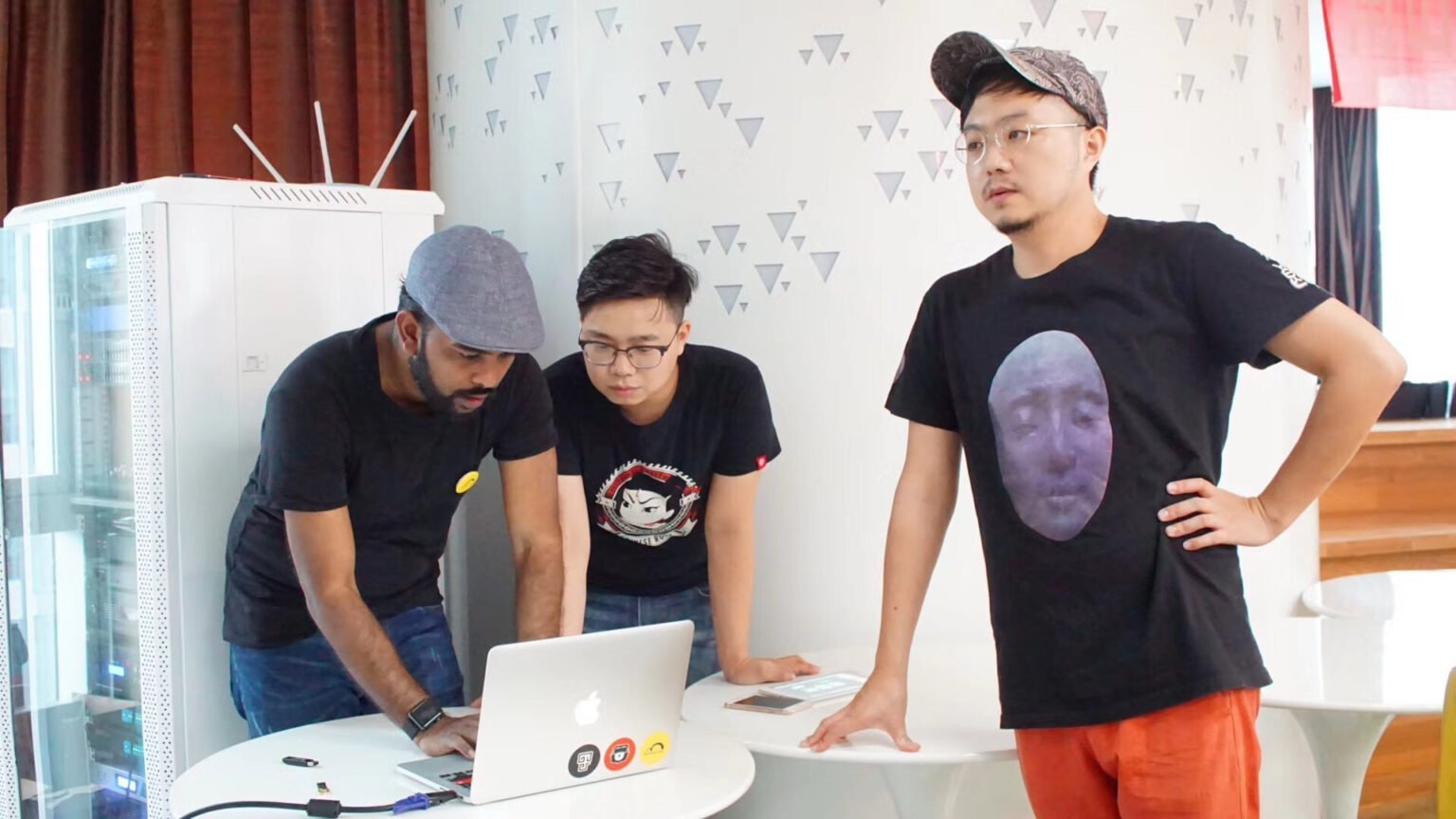 Three participants discussing a laptop at a workshop