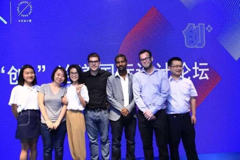 A group posing in front of a design-event backdrop